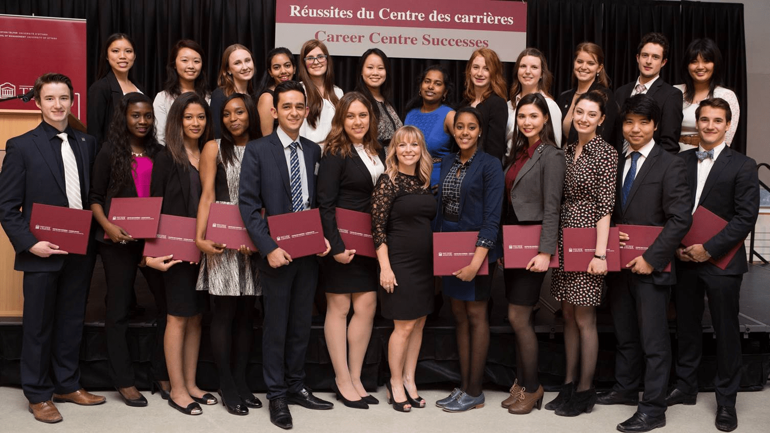 Amanda Richardson and a group of students holding red folders pose for a photo at a Telfer Career Center event.