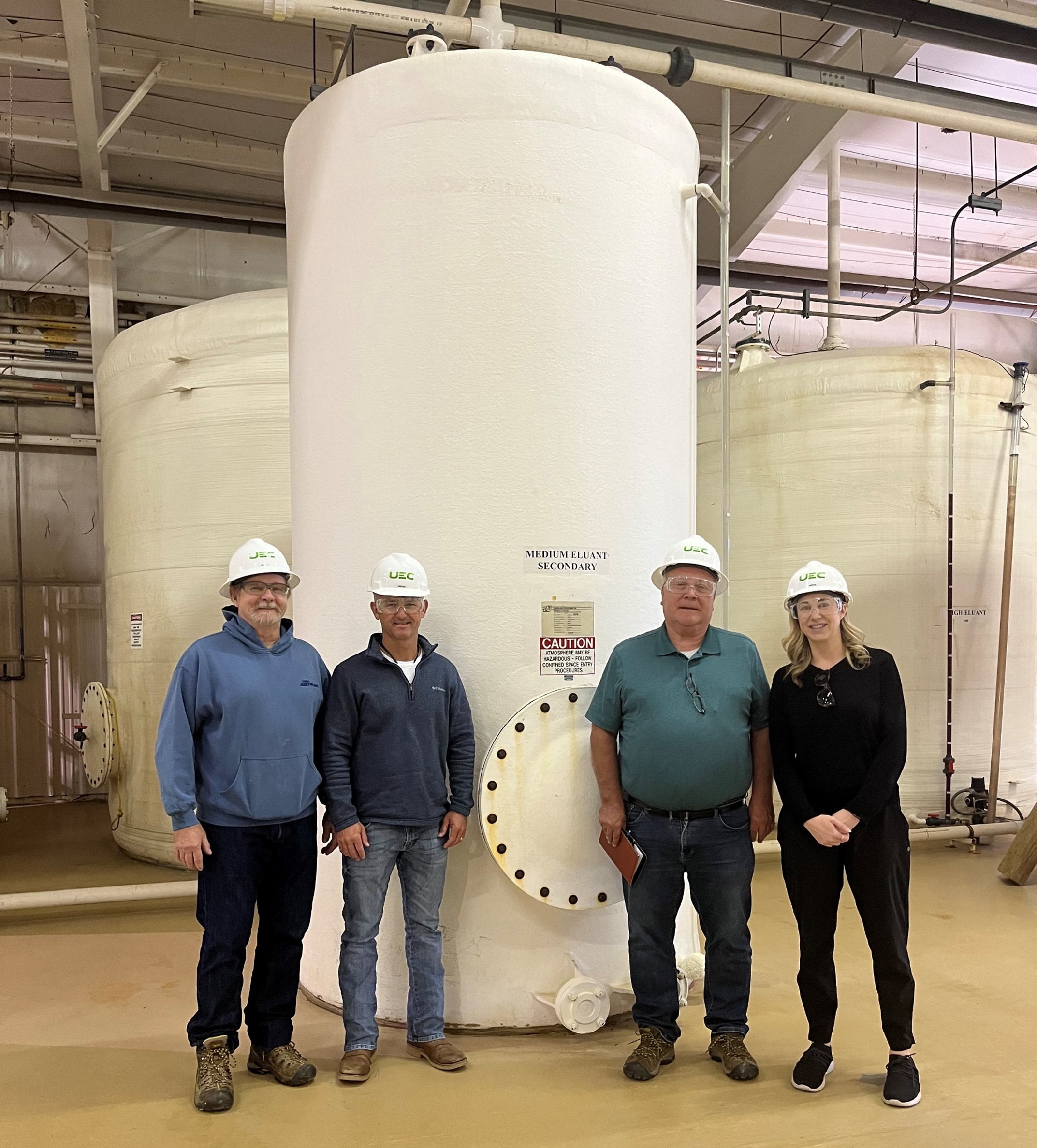 Katherine et trois de ses collègues masculins prennent la pose devant un grand réservoir cylindrique servant à traiter l’uranium