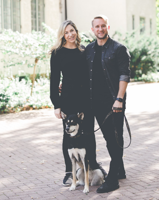 Katherine standing next to her partner, Alex, who is holding their dog on a leash.