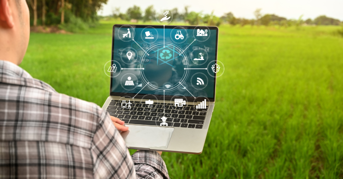 Man holding laptop in front of a green field