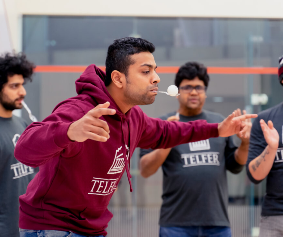 mba student holding an egg in their mouth on a spoon for a challenge