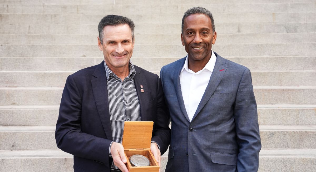 Myron Tetreault holding the R. Trudeau Medal beside Dean Brutus