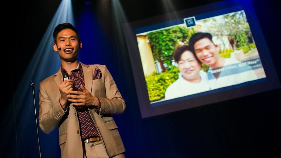Nathon standing on a stage with a picture of him and his mom projected in the background.