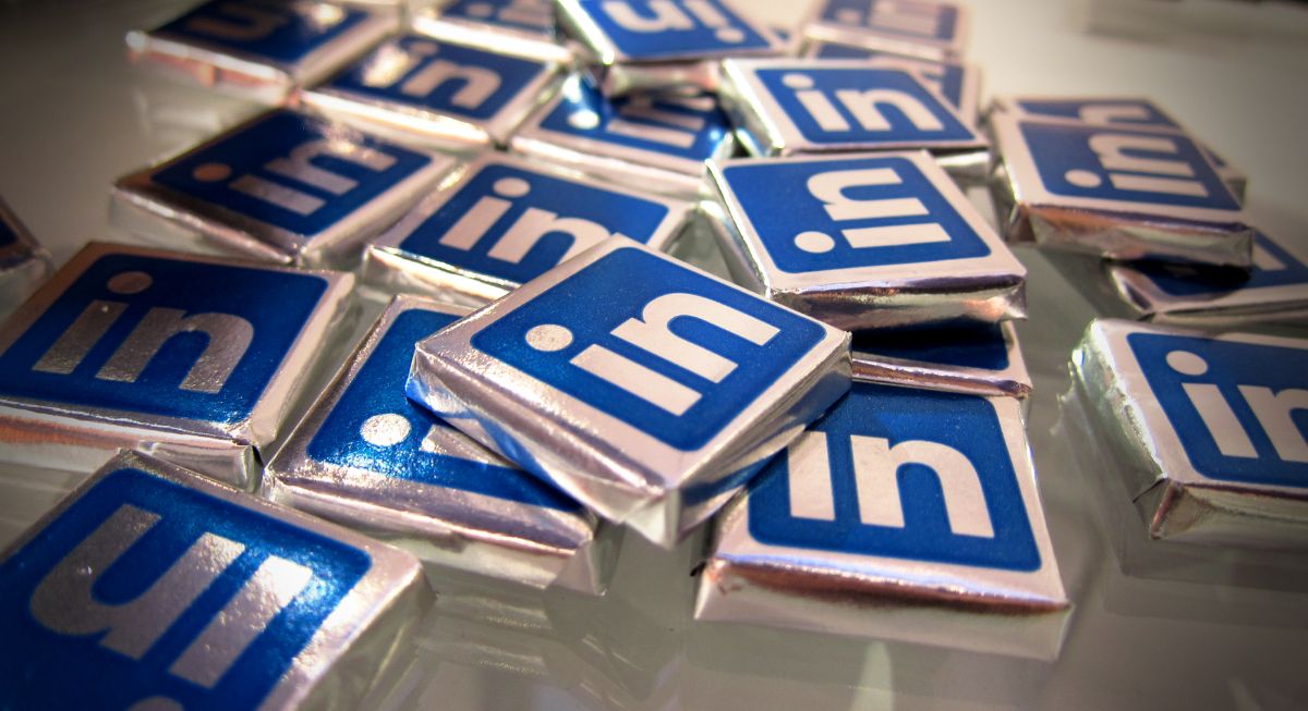 On a table, many little square chocolates wrapped in foil paper covered with a LinkedIn logo sticker.
