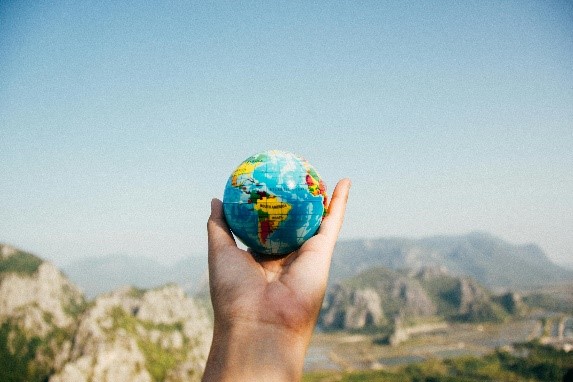 outdoor photo with a human hand holding a miniature model of earth