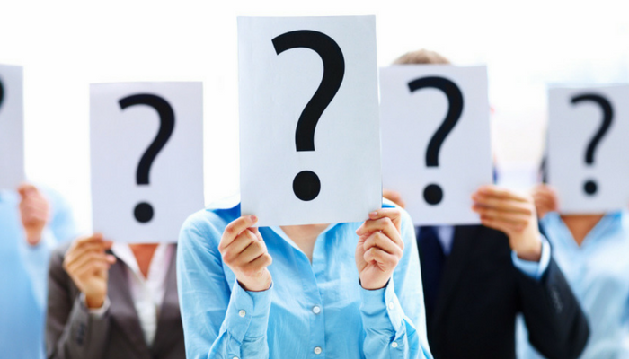 People hiding their face with white signs showing black question marks.