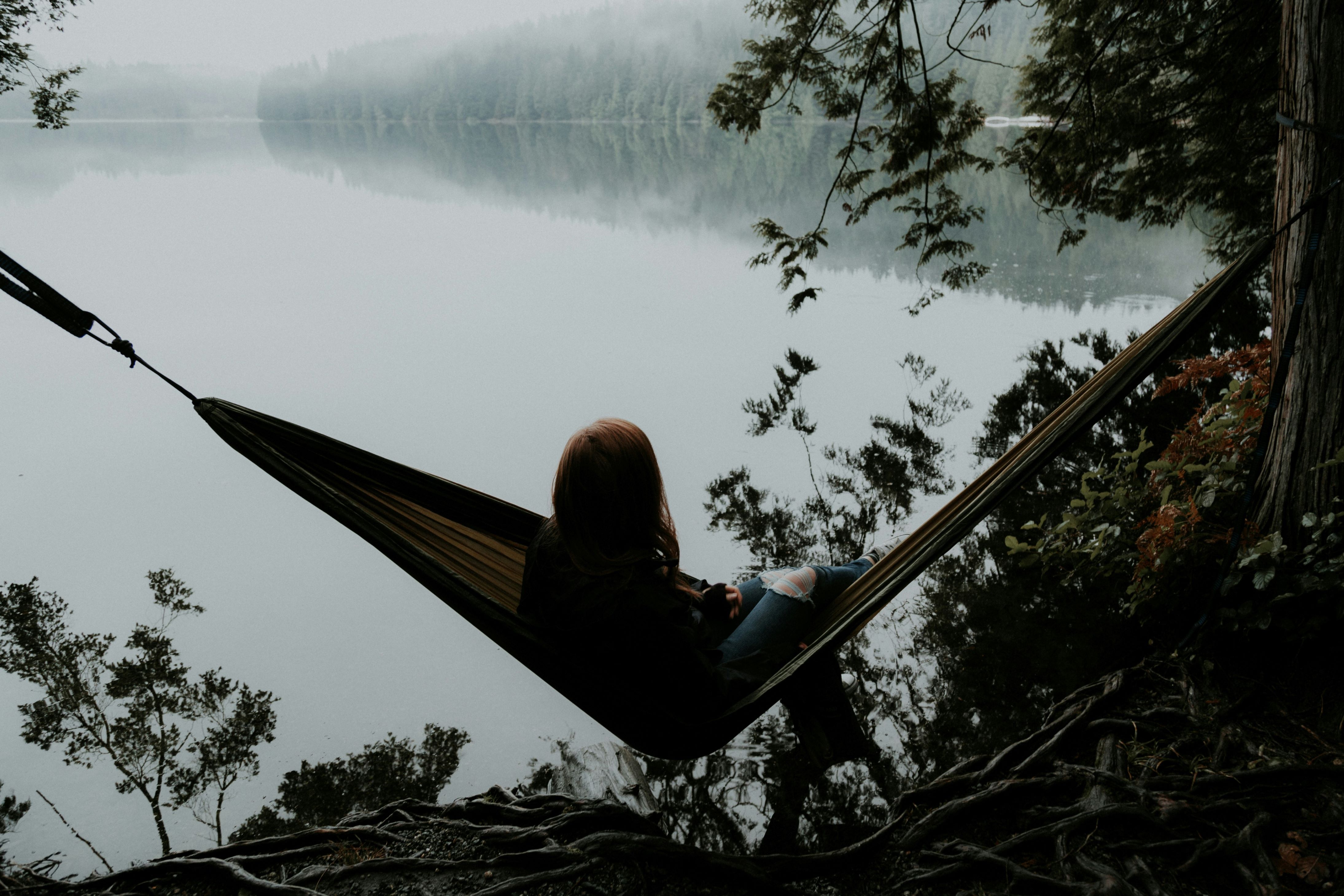 Person sitting in a hamac overlooking a body of water