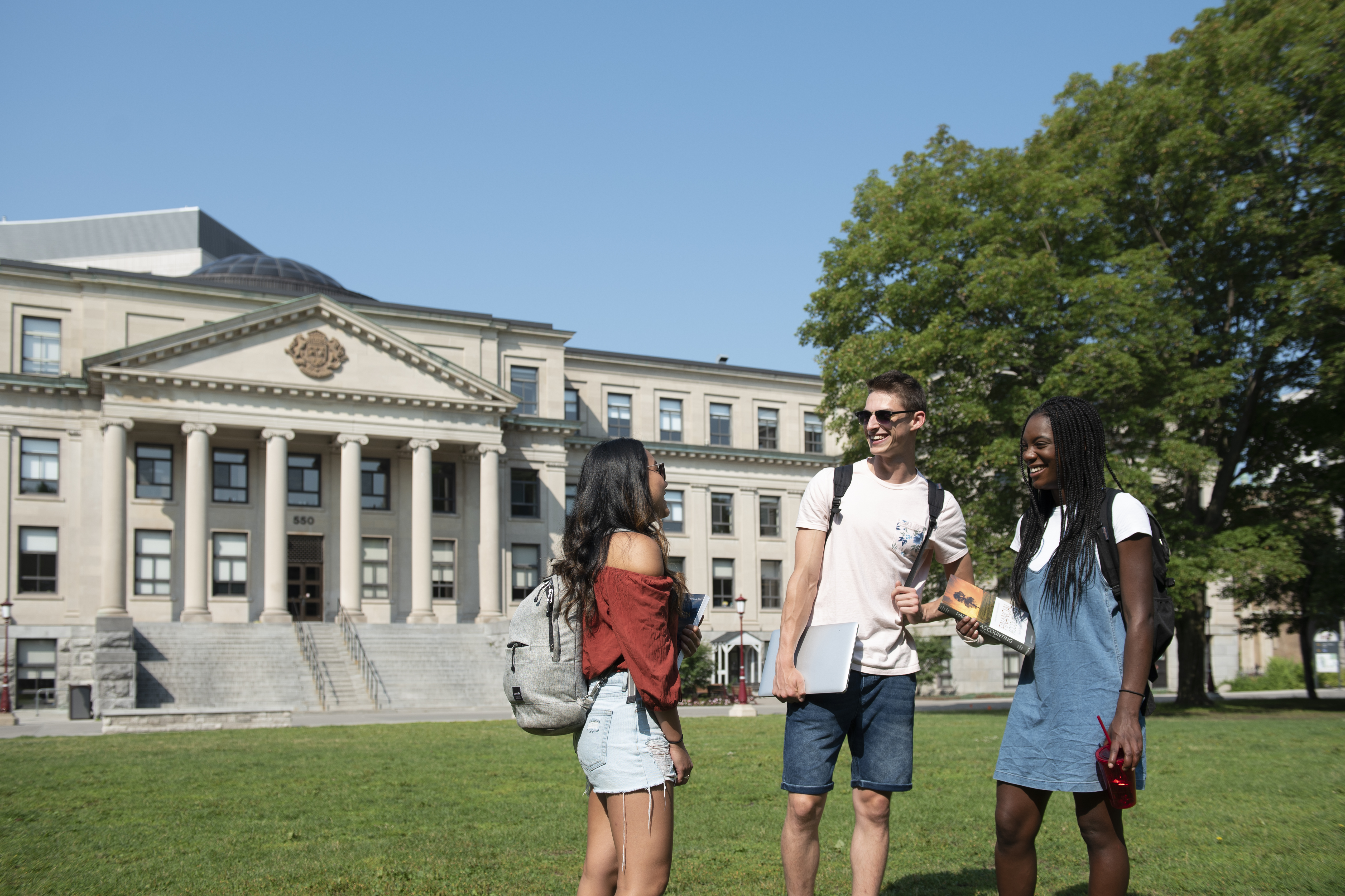 Telfer Students talking and smiling on Tabaret Lawn at uOttawa