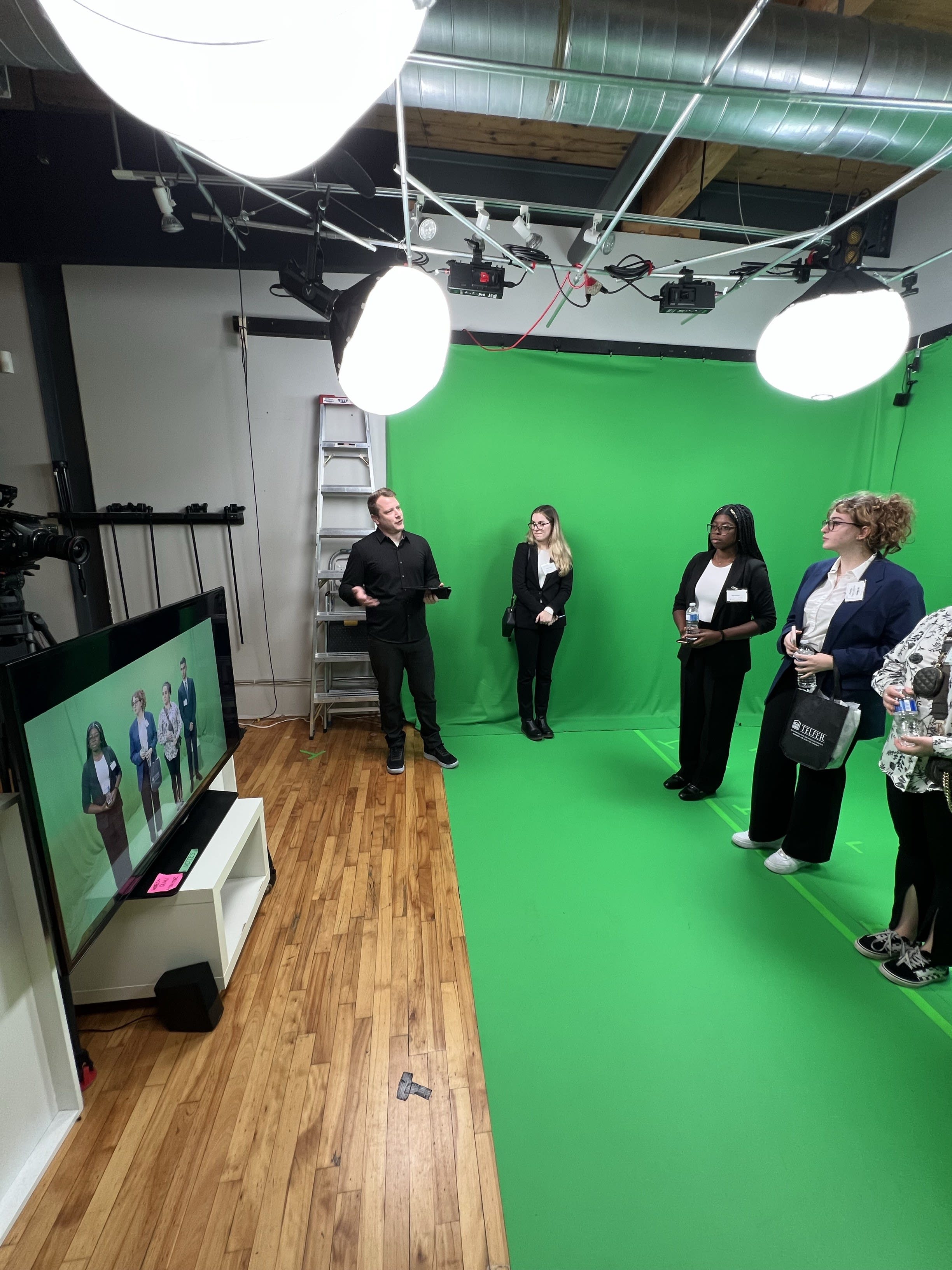 Un groupe d'étudiants de Telfer réunis autour d'un écran vert sur le plateau de tournage avec Gareth Musico.