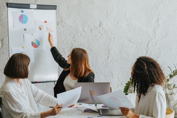 Three women sitting in an office discussing financial charts