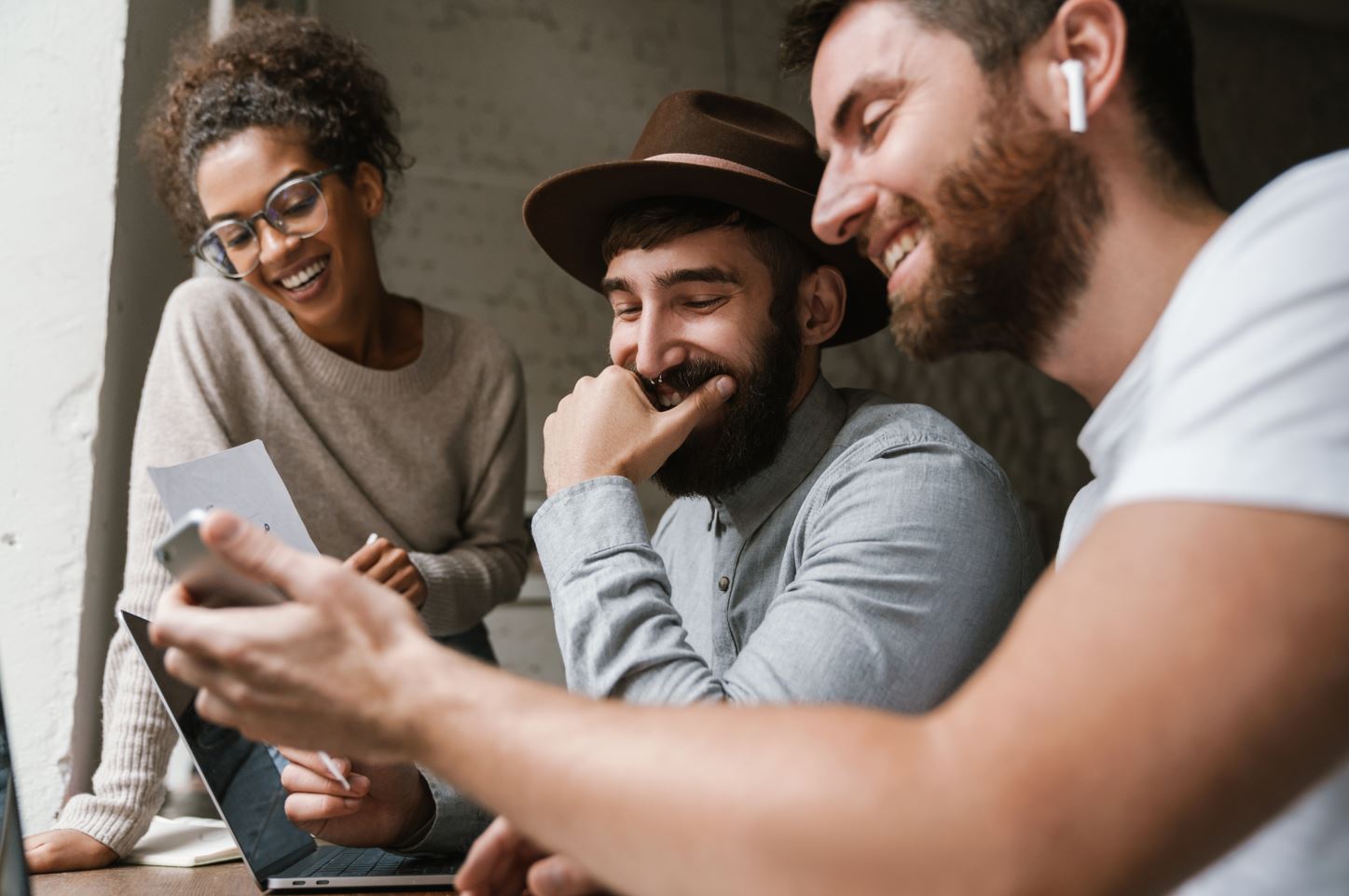 Trois étudiants en marketing numérique qui regardent un cellulaire.