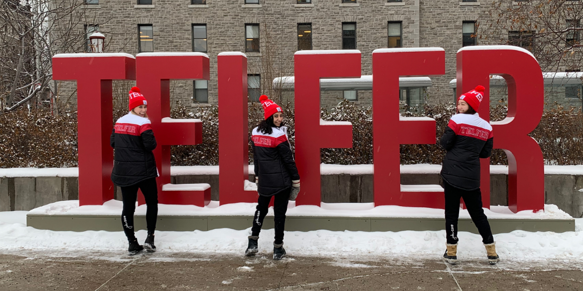 Trois étudiants souriant devant le signe Telfer