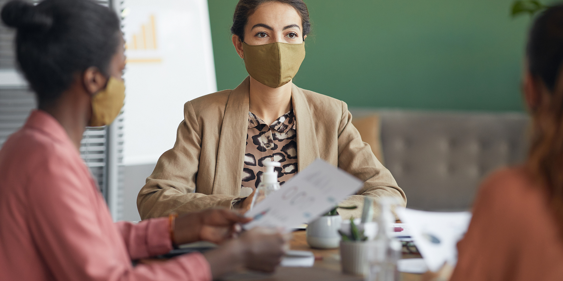 Trois femmes d'affaires portant des masques discutent autour d'une table