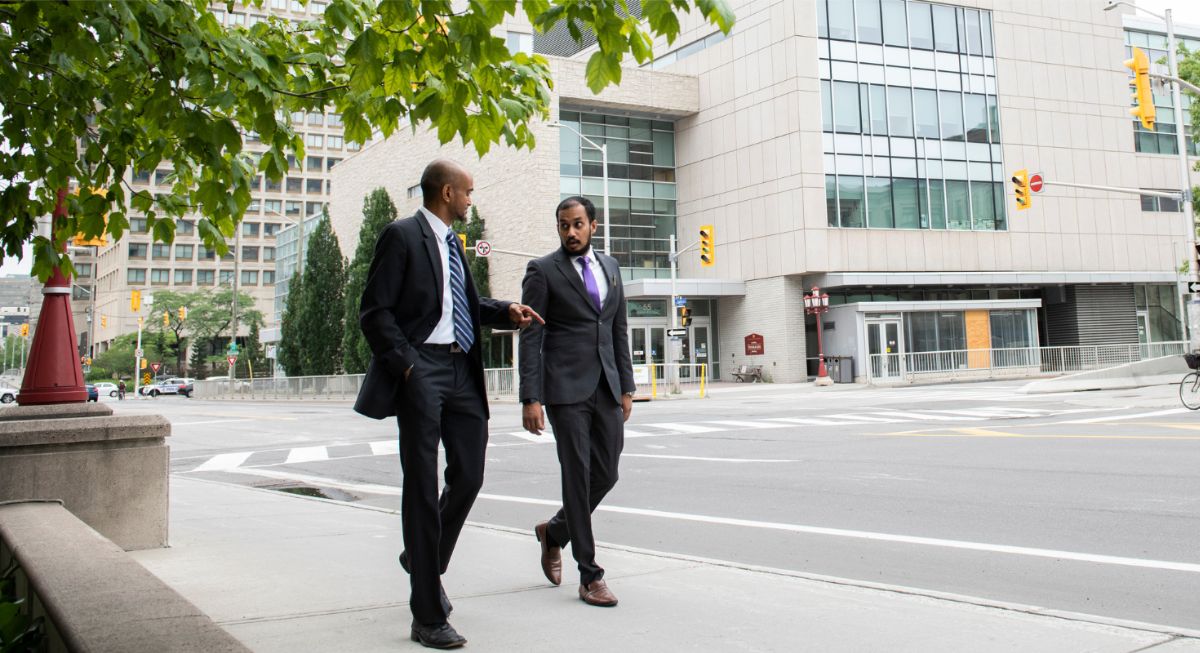 Two male MBA students walking and discussing business outside of the Desmarais building