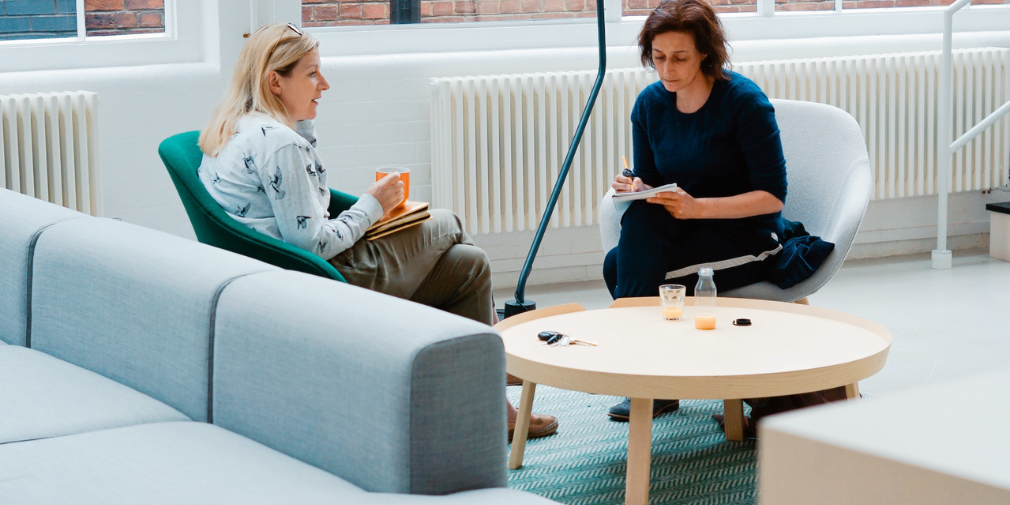 Two people seated across from one another taking notes