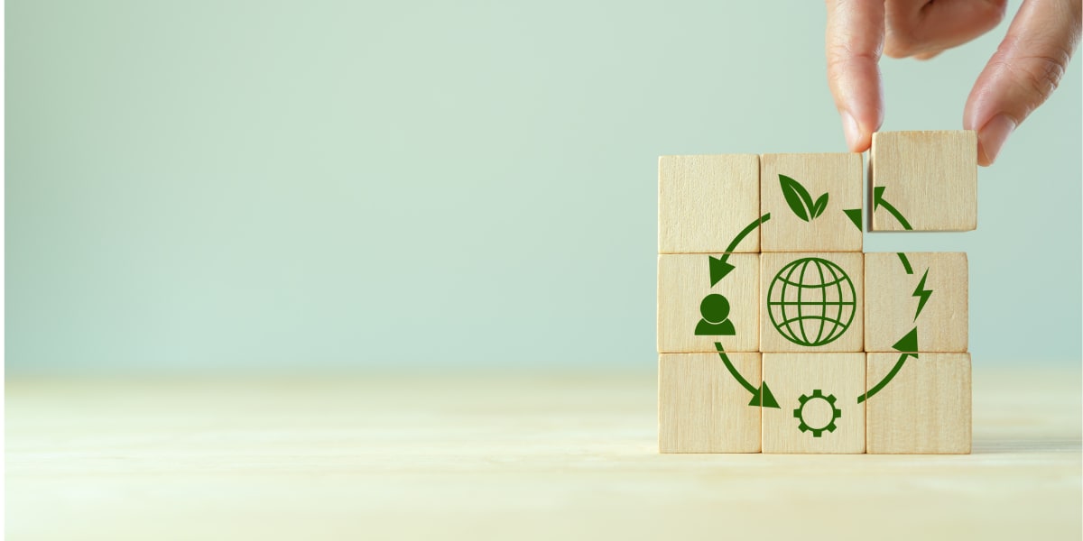 a hand putting together the different components that contribute to sustainiblity drawn on cubes