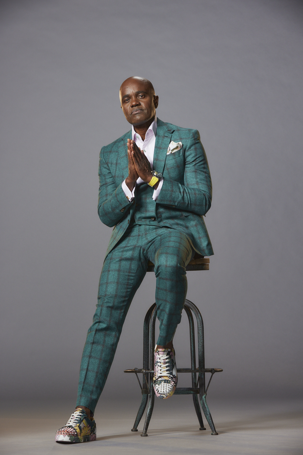Wes Hall sitting on a stool wearing a plaid suit.