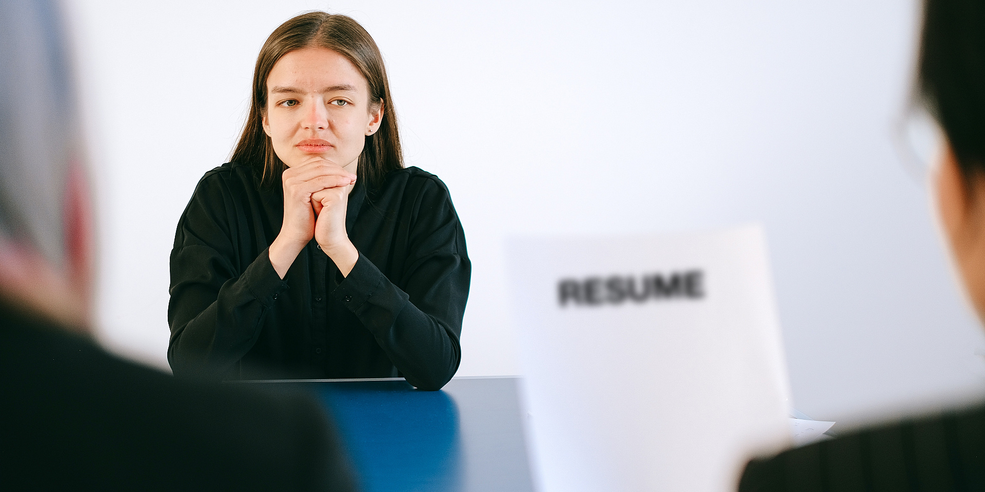 Woman waiting as two individuals read a paper with the word 