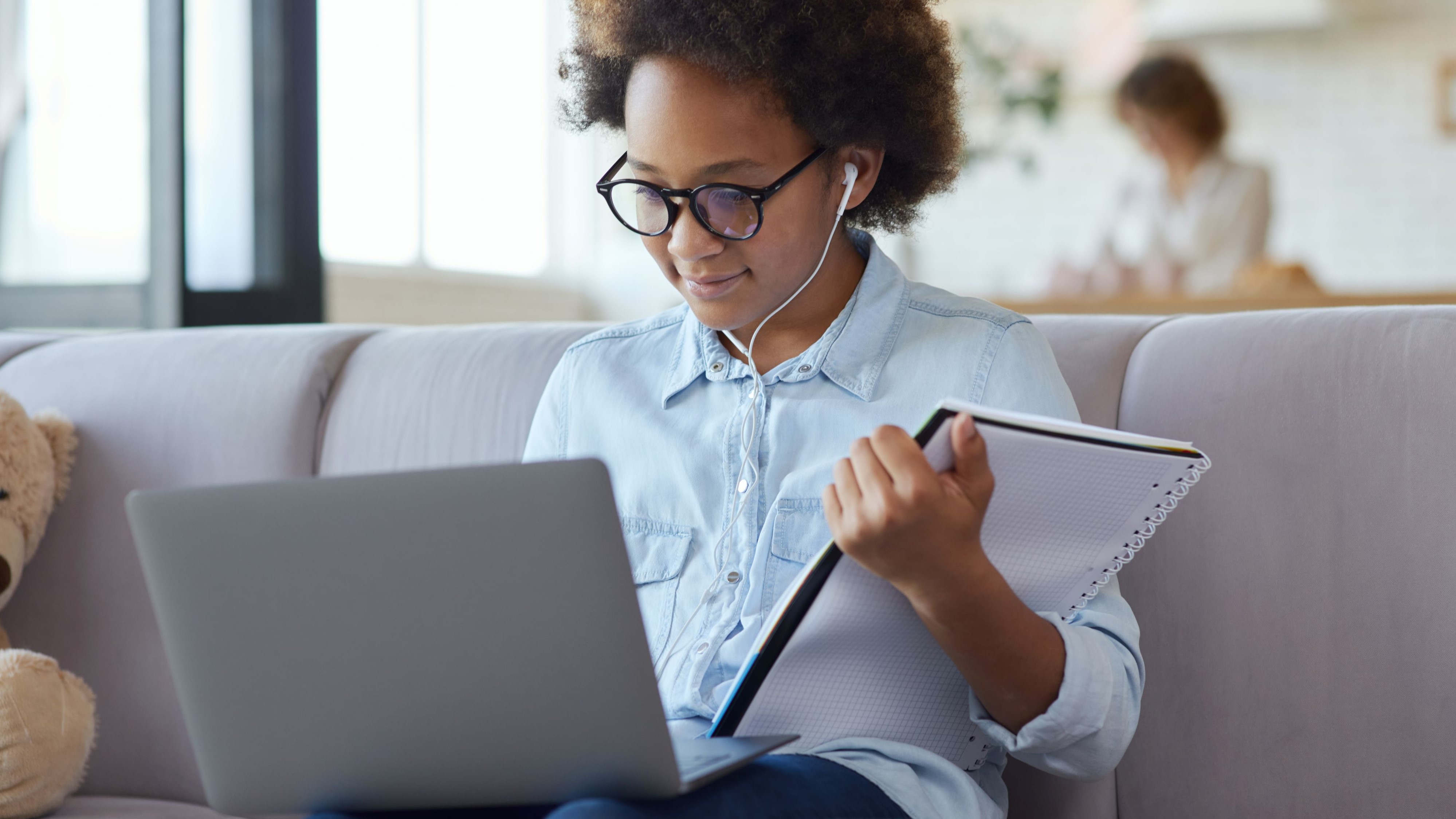 Young stuent looking at a laptop and holding a notebook